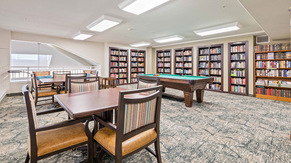 The library at Oak Park Retirement with shelves of books and comfortable seating